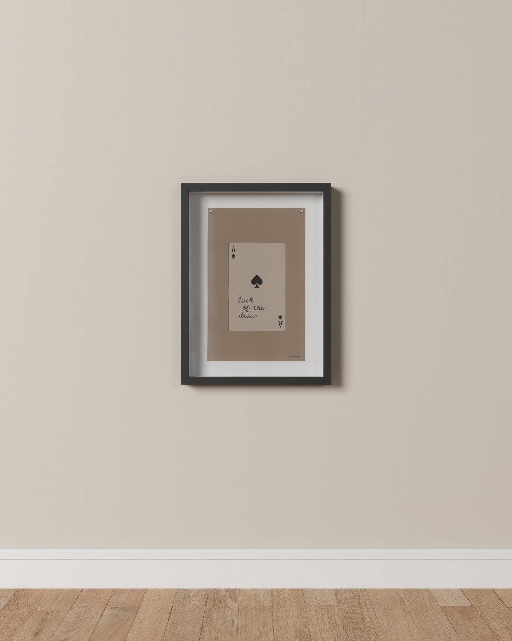 Framed playing card artwork on a beige wall