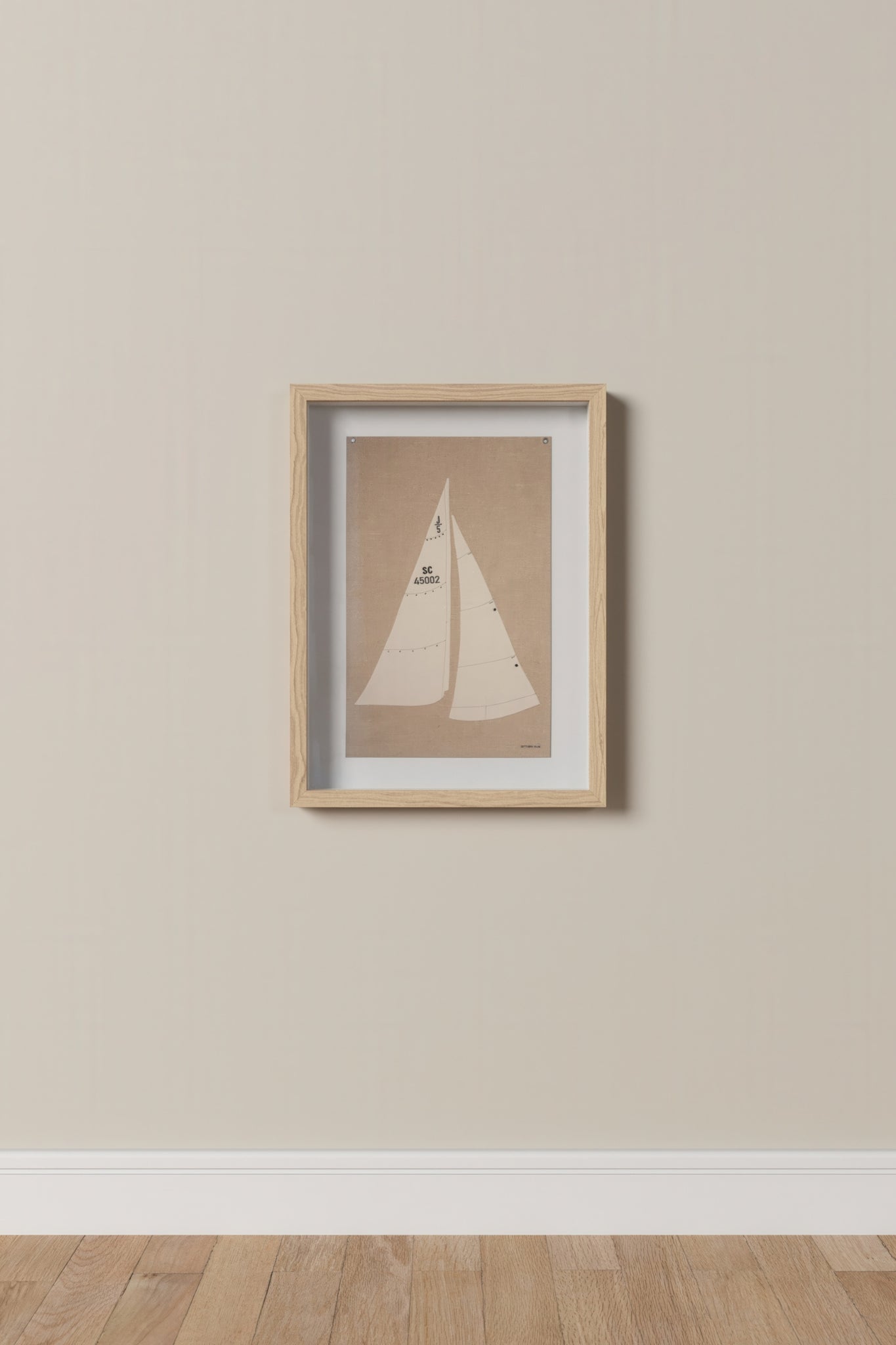 Framed artwork of a sailboat on a beige wall.