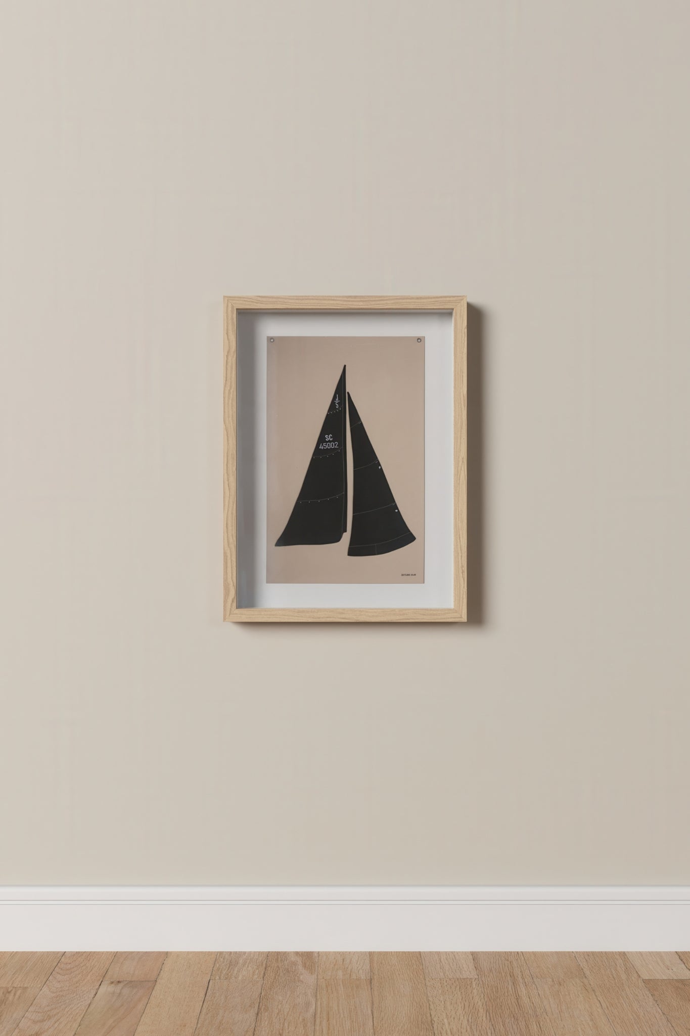 Framed artwork of a sailboat on a beige wall.